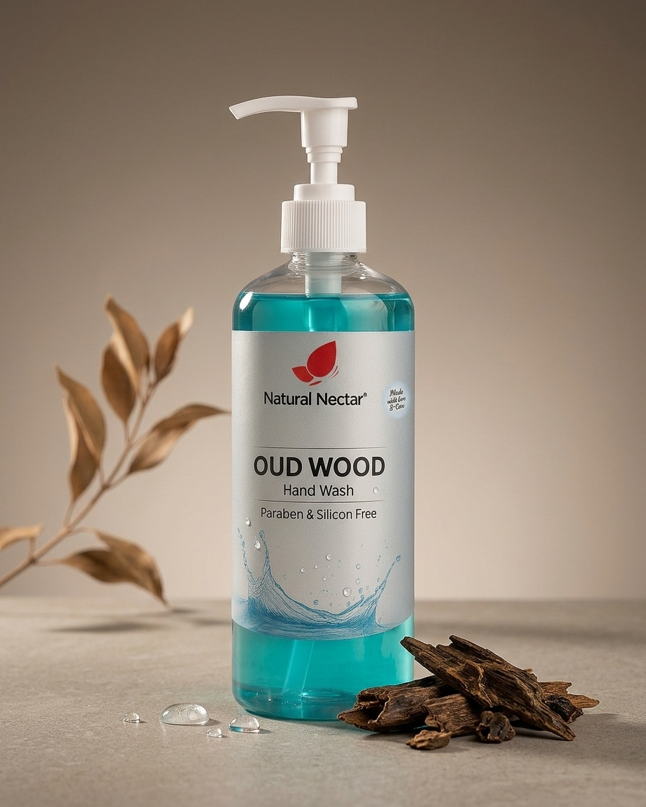 Natural Nectar Oud Wood Hand Wash in a clear pump bottle filled with blue liquid, styled on a neutral beige surface with dried leaves and bark props.