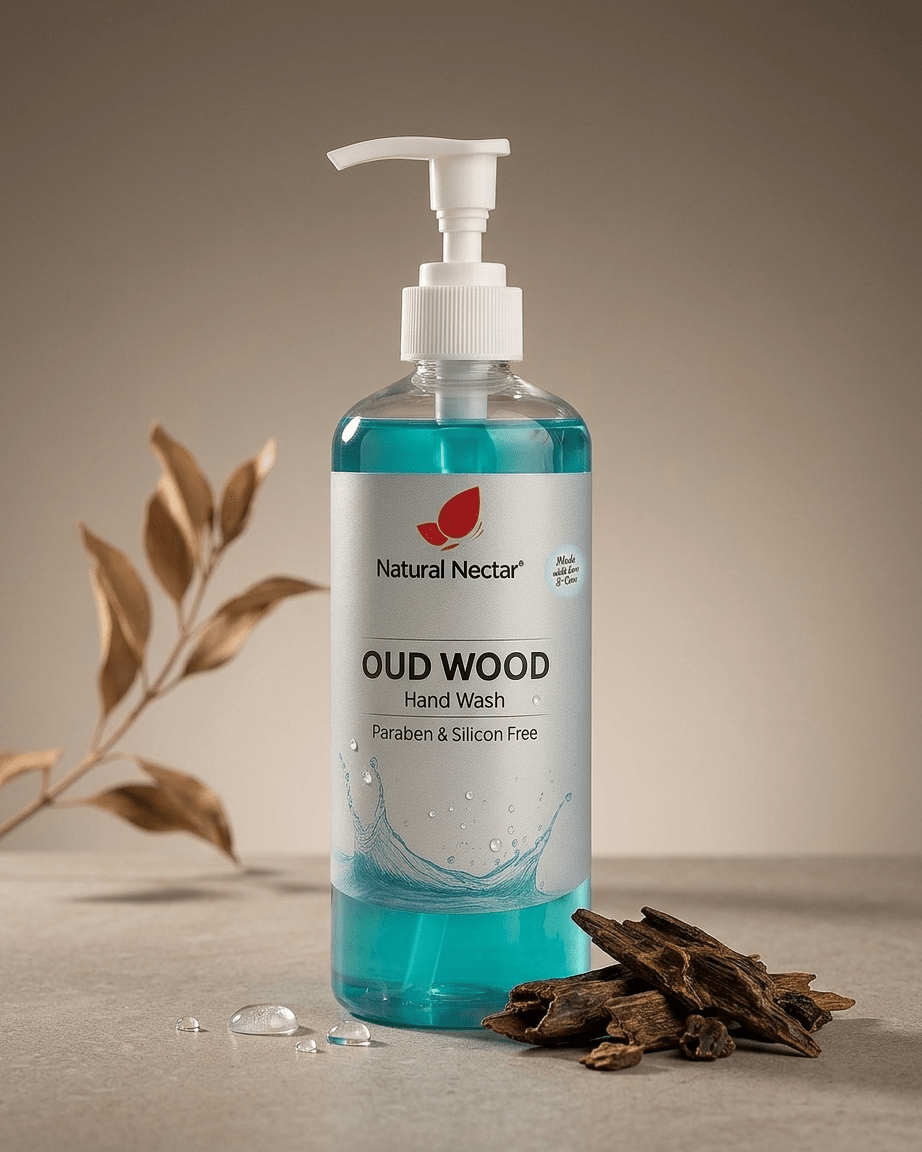 Natural Nectar Oud Wood Hand Wash in a clear pump bottle with blue liquid, styled on a neutral beige surface with dried leaves and bark props.