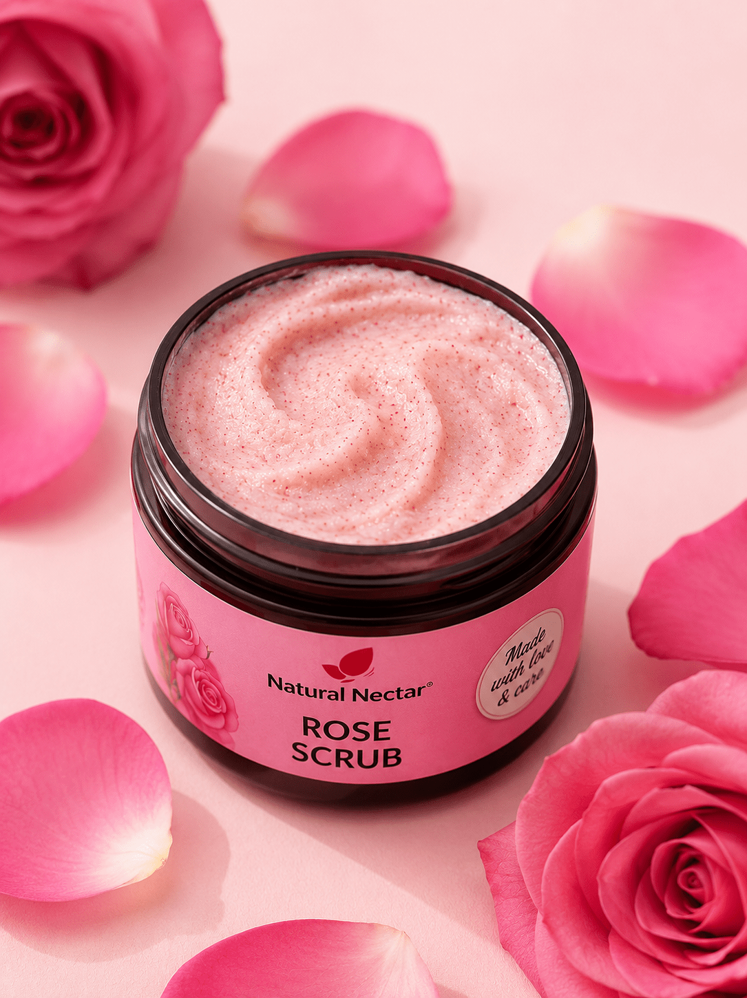A jar of Natural Nectar Rose Scrub with pink whipped scrub visible inside, surrounded by fresh pink rose petals and roses.